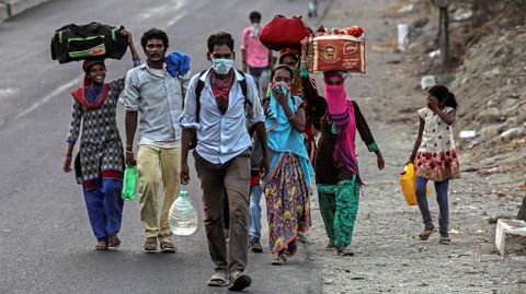 Trabajadores y sus familias  se desplazan a pie por una autopista en las afueras de Munbai, India