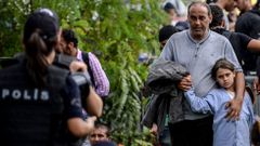 Un hombre y una niña esperan a que la policía turca los deje pasar para seguir una ruta hacia Europa que pasa por Estambul.