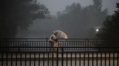 Una mujer y una ni�a tratan de taparse con un paraguas.