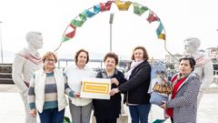 Representantes de las dos entidades de palilleiras, junto al monumento dedicado a la danza de arcos, en el paseo mar�timo