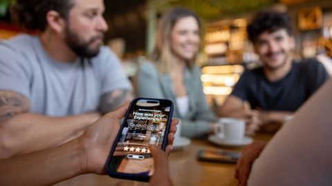 Foto de recurso de varias personas en un restaurante valorando con el m&oacute;vil el servicio prestado