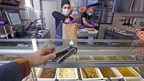 Un cliente pagando con el m�vil en un establecimiento de comida preparada.