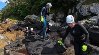Participantes en una de las salidas por la costa, con neopreno, guantes y casco, por las rocas de la costa de Cedeira