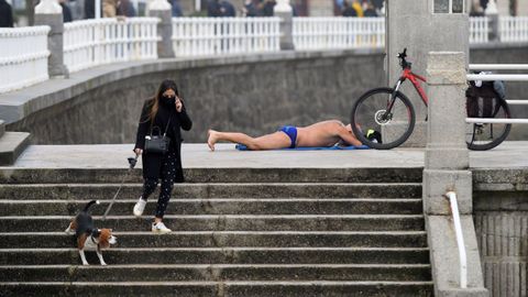 Una mujer con mascarilla y su perro acceden a la playa de San Lorenzo de Gij�n 