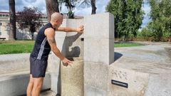 Un usuario, comprobando este lunes que la fuente termal de Os Remedios no funciona.