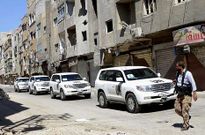 Un rebelde cruza delante del convoy de expertos de la ONU en el barrio de Zamalka, en Damasco.