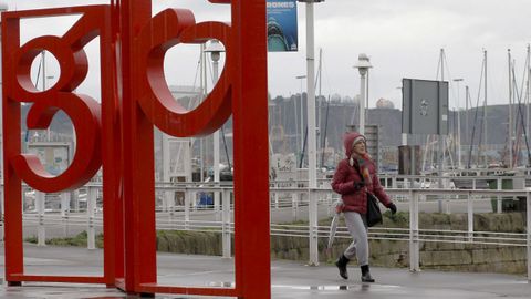 Una mujer camina por el puerto deportivo de Gijón un día de lluvia