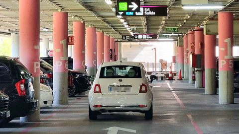 Un coche, en el aparcamiento de Peinador, cerca de un cartel de salida.