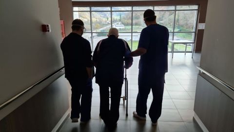 Dos trabajadores acompa�an a un usuario de la residencia del Montep�o en Felechosa