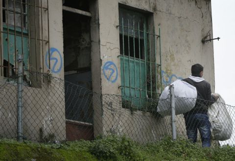 Un vendedor ilegal sale de la casa abandonada de Puerto Rico con sus petates. 