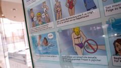 Un cartel con normas de convivencia colgado en una piscina.