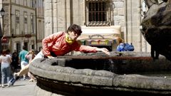 Una peregrina se refresca en la fuente de la plaza de Prateras, en Santiago de Compostela