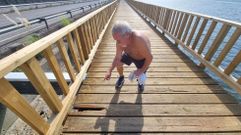 Un vecino se�ala el agujero dejado por los v�ndalos tras arrancar una de las luminarias en la pasarela de Os Praceres