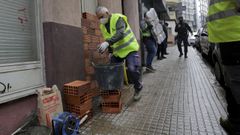 Un alba�il tapia la puerta de una vivienda que fue okupada, en A Coru�a