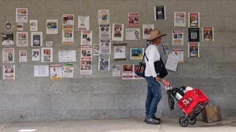Un hombre camina ante carteles de personas desaparecidas por los se�smos, en La Guaira