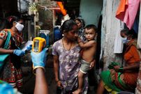 Un sanitario tomando la temperatura a residentes de Mumbai, en la India