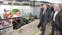 El ministro Luis Planas, en el centro, con Basilio Otero (patr�n mayor burelense) y Carmela L�pez (alcaldesa burelense) pasando al lado de un pesquero en el puerto de Burela a principios de diciembre del 2024.