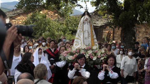 Mujeres vestidas con el traje tradicional gallego se turnan para llevar la imagen de la Virgen en procesin entre las casas de A Ermida