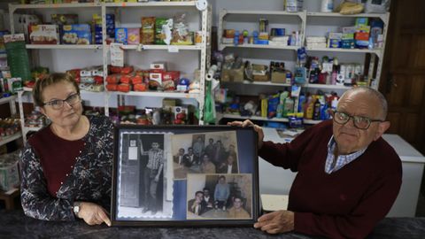 Rosa y Jos sostienenantiguas fotografas que decoran la taberna, en una de las que se le ve a la la puerta del negocio, abierto en 1967