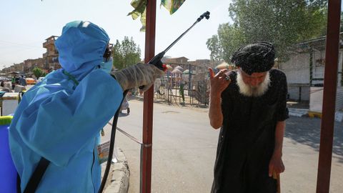 Un t�cnico desinfecta a un transeh�nte en Irak