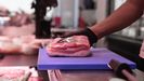 Un carnicero muetra un despiece de cerdo en un mercado de Madrid