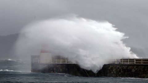 Las olas pasan por encima del faro del puerto de Corrubedo