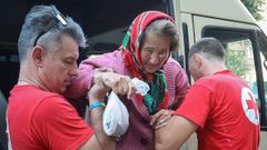 Voluntarios de la Cruz Roja ayudan a una anciana evacuada de Kupiansk-Vuzlovyi