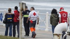 El padre (2d) y la madre (i) del desaparecido reciben apoyo emocional mientras miembros del operativo de b�squeda y rescate peinan este martes la zona donde desapareci� el joven de 19 a�os desaparecido ayer, lunes, cuando se ba�aba en la playa de Salinas
