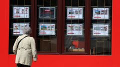 Una mujer consulta anuncios de pisos en venta en una inmobiliaria de Boiro.
