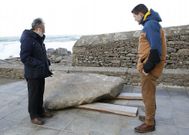 Dos visitantes observan el trozo de 3,6 toneladas que se encuentra en el atrio del santuario. 