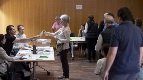 Una mujer deposita su voto mientras en otra mesa aguarda una larga cola en el Centro Cvico Villa Florida el da en que ms de cinco millones de ciudadanos estn llamados este domingo a las urnas en las elecciones catalanas