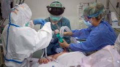 Una doctora y dos enfermeras de la unidad de cuidados intensivos del Hospital Santa Lucia de Cartagena atienden a un paciente con covid-19.