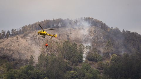 Helic�ptero durante las labores de extinci�n del incendio forestal en Grado, Asturias