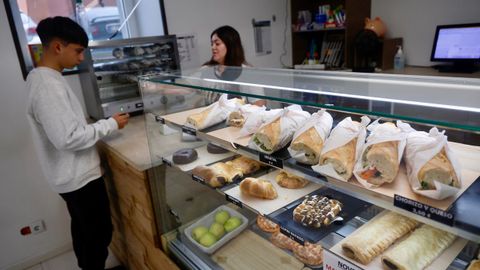 Marta, empleada de la tienda de alimentacin El Pilar, sirve un bocadillo a un estudiante del instituto.