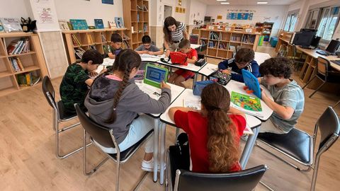 La directora del colegio de Bóveda, Ana de la Fuente, con varios alumnos en la biblioteca del centro