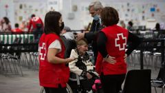 Dos trabajadoras de Cruz Roja con una anciana ucraniana