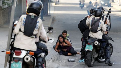 Agentes de seguridad rodean a dos manifestantes afectados por un ataque con bombas lacrim�genas