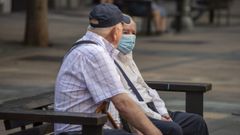 Dos hombres sentados en un parque de Vitoria, uno de ellos con mascarilla