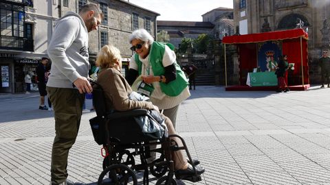 Una voluntaria pone la pegatina de la AECC a una señora tras aportar en el Día de la Cuestación, que se celebra este jueves durante toda la jornada en Pontevedra