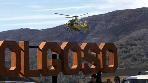 El helicptero de emergencias momentos antes de tomar tierra en Folgoso, con el letrero turstico con el nombre del municipio en primer plano