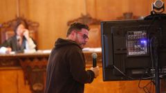 Uno de los acusados, ayer en el juicio, observando un v�deo