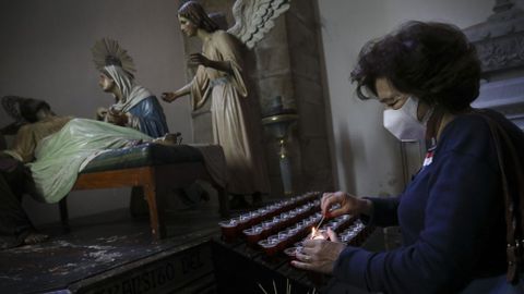 Una feligresa enciende una vela en la iglesia de San Francisco de Santiago