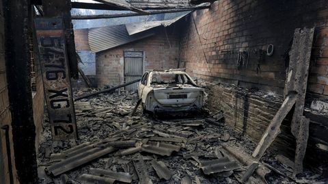 Un coche destruido por el fuego entre los restos de una de las casas quemadas en Vilar do Courel