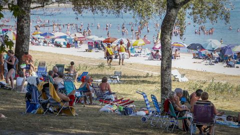Gente aprovechando la sombra de los árboles en la playa de Barraña