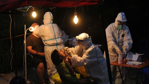 Los trabajadores con trajes protectores recogen hisopos para la prueba de cido nucleico en un sitio de prueba improvisado, luego del brote de la enfermedad del coronavirus, en Dalian, provincia de Liaoning, China