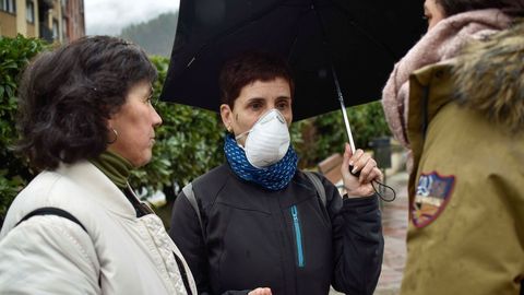 Tres vecinas de Ermua, una de ellas con mascarilla, conversan en las inmediaciones del vertedero que sigue ardiendo en la localidad vecina de Zaldibar