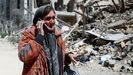 Una mujer habla por tel�fono junto a un edificio residencial destruido en Teher�n.