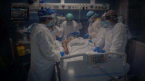 Trabajadores sanitarios protegidos atienden a un paciente en la Unidad de Cuidados Intensivos �UCI- del Hospital del Mar, en Barcelona