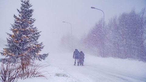 Dos personas caminan por una carretera en medio de fuertes nevadas en Hemavan, en Suecia