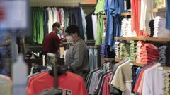 Compradores con mascarilla en una tienda de moda